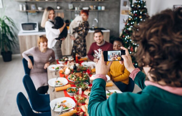 A person with curly hair taking a group holiday photo at the dining table