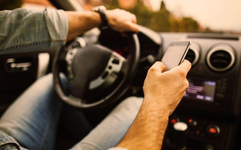 Young man in the car using his phone while driving