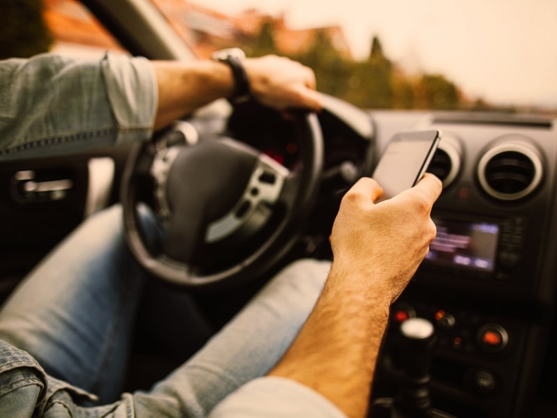 Young man in the car using his phone while driving
