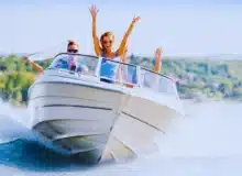 Group of young people with raised hands enjoying in a speedboat ride.