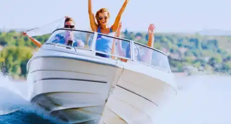 Group of young people with raised hands enjoying in a speedboat ride.