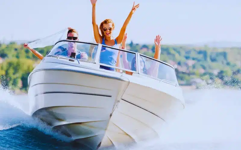 Group of young people with raised hands enjoying in a speedboat ride.