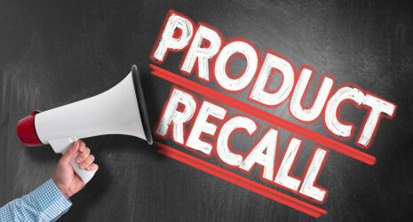 Hand holding megaphone or bullhorn against blackboard with text PRODUCT RECALL.