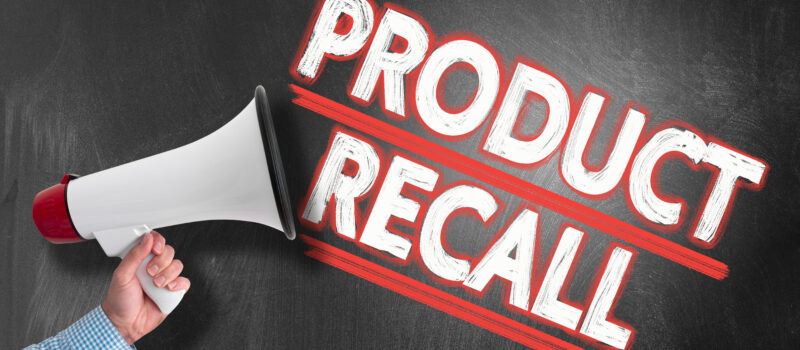 Hand holding megaphone or bullhorn against blackboard with text PRODUCT RECALL.