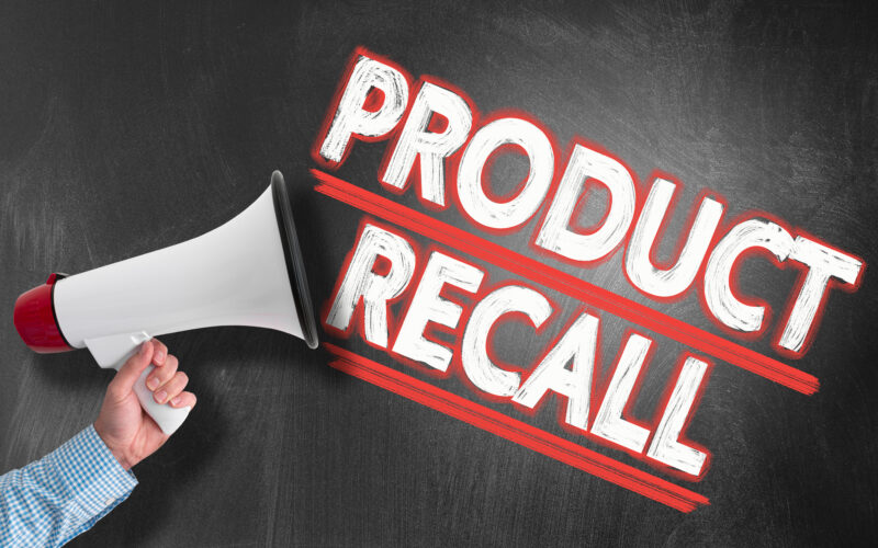 Hand holding megaphone or bullhorn against blackboard with text PRODUCT RECALL.