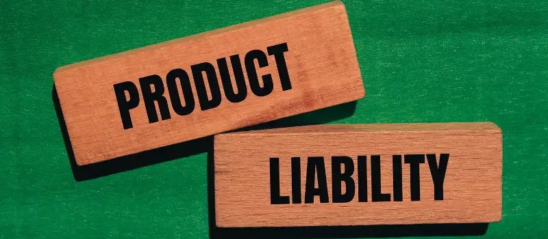 Product liability words written on wooden blocks with green background.