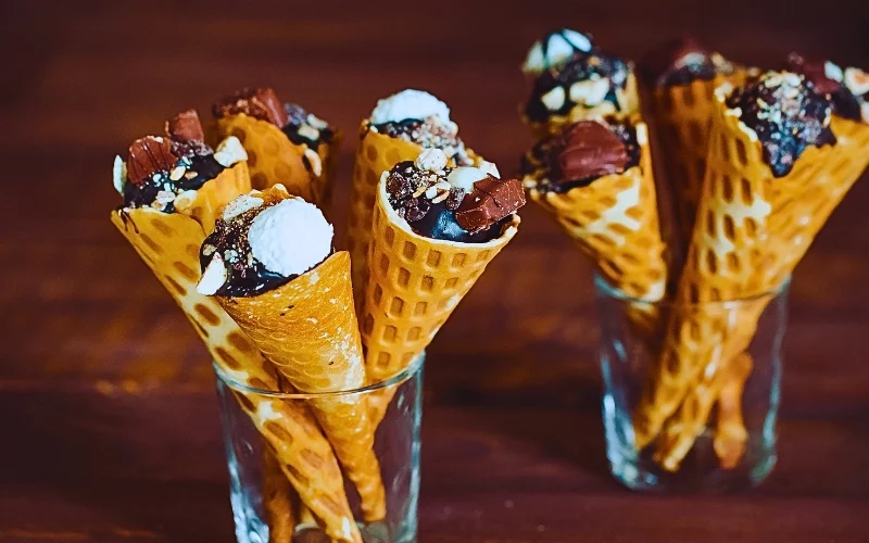 Tasty chocolate ice cream in waffle cone on brown wooden background.