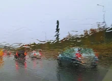 Vehicles road seen from wet car windshield.