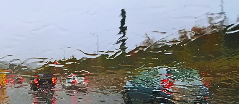 Vehicles road seen from wet car windshield.