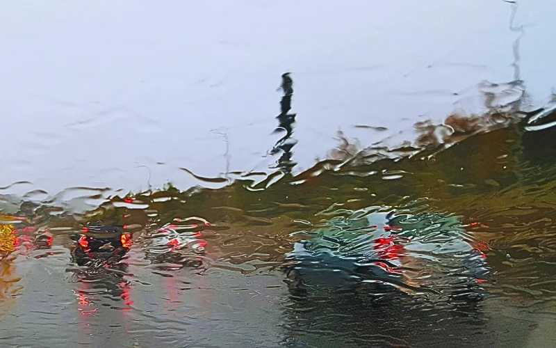 Vehicles road seen from wet car windshield.