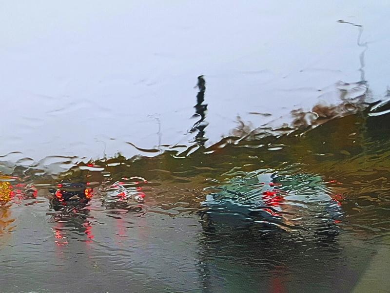 Vehicles road seen from wet car windshield.