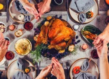 a Thanksgiving dinner scene where several people are holding hands around a table.